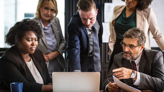 5 employees gathered around a laptop understanding indirect R&D activitites for R&D tax credits